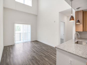 an empty living room and kitchen with a sink and a window